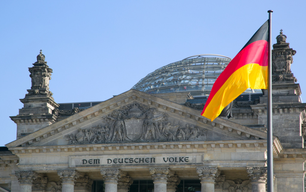 Giebel des Reichstagsgeb&auml;udes mit der Inschrift Dem Deutschen Volke und wehender Deutschlandfahne.