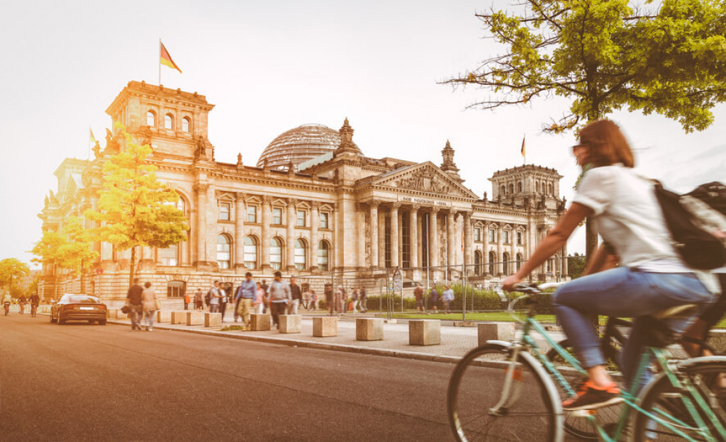 Radfahrerin f&auml;hrt im Abendlicht am Berliner Reichstagsgeb&auml;ude vorbei.